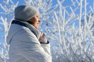 contento giovane donna in posa nel nevoso inverno parco foto