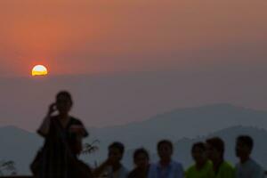 persone in piedi vedere tramonto con montagna foto