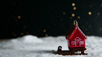 Natale albero giocattolo nel il modulo di un' rosso Casa su un' slitta nel il neve. Natale, nuovo anno sfondo foto