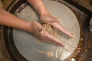 vasaio ragazza lavori su di vasaio ruota, fabbricazione ceramica pentola su di argilla nel ceramica laboratorio foto