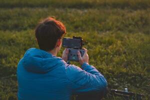 giovane direttore della fotografia spara parti di un' film utilizzando un' tecnologico Prodotto chiamato un' drone. registrazione il tramonto a partire dal un aereo Visualizza foto