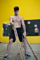 uomo in forma che si allena con le corde da battaglia in palestra foto