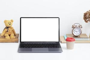 scrivania con schermo vuoto per laptop, orsacchiotto vintage e una tazza di bevanda. lavoro online, concetto freelance foto