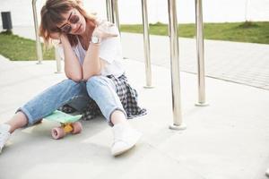 una bella ragazza si sta divertendo nel parco e cavalca uno skateboard foto