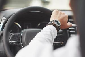 un uomo d'affari guida la sua auto, si muove sul volante. mano con orologio foto