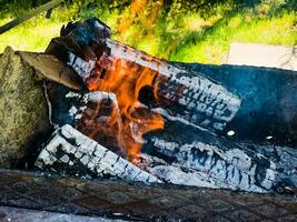 avvicinamento di un' fuoco con legna da ardere, carboni e cenere. foto