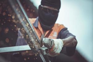 gli operai tagliano le capriate del tetto d'acciaio nella costruzione. foto