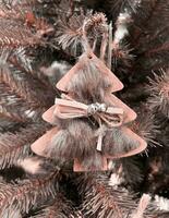 zero sciupare. eco Natale albero arredamento giocattolo - di legno pendente è decorato con pelliccia, nastro e campana, senza plastica. colore di il anno 2024 - pesca peluria. foto