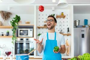 allegro giovane uomo lanciare verdure nel aria a il cucina foto