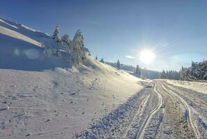 sole, neve e auto brani su il strada nel il inverno nel il montagna. il concetto di inverno viaggio di macchina. foto