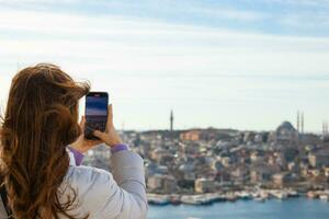 un' donna assunzione foto di Istanbul con sua mobile Telefono su galata Torre