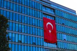 un' Turco bandiera sospeso su il moderno costruzione. Turco economia concetto foto