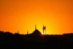 fatih moschea silhouette a tramonto con bandiera di turkiye foto