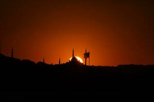 fatih moschea e bandiera con sole a tramonto. silhouette di Istanbul foto