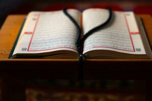islamico sfondo foto. sfocato santo Corano e rosario su il leggio. foto