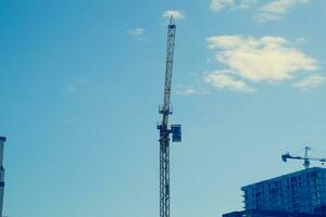 Torre edificio gru contro il blu cielo e sole. costruzione di nuovo edifici con un' gru. Torre gru foto