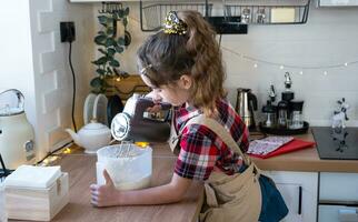 figlia apprendimento per cucinare aiuta nel il bianca cucina impastare il Impasto nel il ciotola per Pan di zenzero e biscotti per Natale e nuovo anno. mettere il ingredienti foto