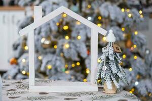 chiave su Natale albero e minuscolo Casa su accogliente casa con Natale arredamento su tavolo di festivo bianca cucina. regalo per nuovo anno. assicurazione, in movimento per nuovo Casa, mutuo, affitto e vero tenuta foto