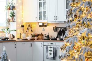 Natale arredamento nel bianca cucina, festivo disordine, villaggio interno con un' nevoso Natale albero e Fata luci. nuovo anno, Natale umore, accogliente casa. foto