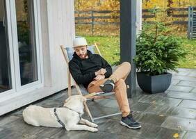 giovane uomo seduta con cane su terrazza foto