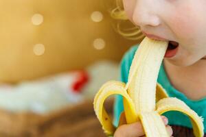 ritratto di un' poco ragazza mangiare un' Banana. il concetto di salutare cibo. un' fresco Presto merenda foto