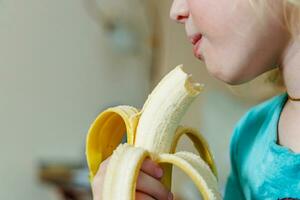 ritratto di un' poco ragazza mangiare un' Banana. il concetto di salutare cibo. un' fresco Presto merenda foto