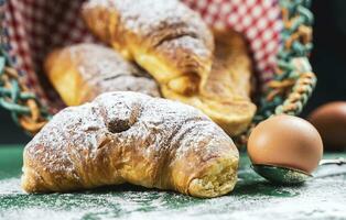 appena al forno Cornetti con in polvere zucchero su un' rustico tavolo foto