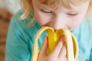 ritratto di un' poco ragazza mangiare un' Banana. il concetto di salutare cibo. un' fresco Presto merenda foto