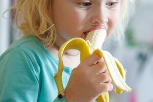 ritratto di un' poco ragazza mangiare un' Banana. il concetto di salutare cibo. un' fresco Presto merenda foto