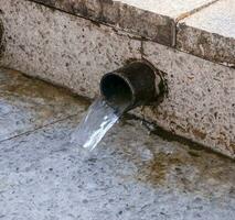 fluente acqua a partire dal il tubo all'aperto foto