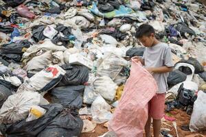 povero bambini su il spazzatura cumulo di rifiuti e Selezione plastica rifiuto per vendere, bambini non nel scuola, povertà. foto