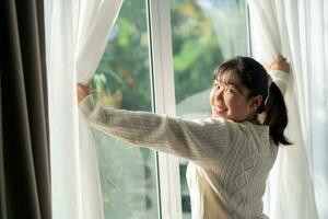 contento donna apertura finestra le tende nel il mattina a casa. foto