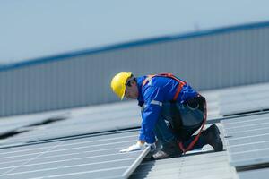 un' tecnico è installazione solare pannelli su il tetto di il magazzino per modificare solare energia in elettrico energia per uso nel fabbriche. foto