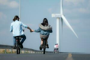 indietro Visualizza di un' giovane donna equitazione un' bicicletta con sua fidanzato su il strada foto