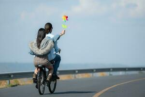 indietro Visualizza di un' giovane donna equitazione un' bicicletta con sua fidanzato su il strada foto