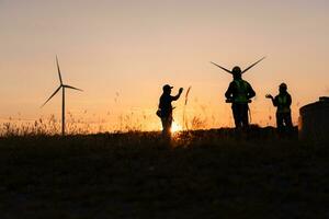 silhouette di ingegnere nel caricare di vento energia contro un' sfondo di vento turbine. foto