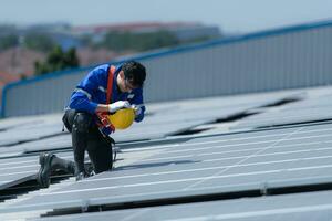 un' tecnico è installazione solare pannelli su il tetto di il magazzino per modificare solare energia in elettrico energia per uso nel fabbriche. foto