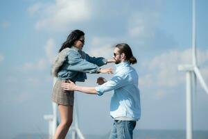 indietro Visualizza di giovane coppia a piedi su il strada con vento turbine nel sfondo foto