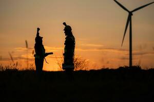 silhouette di ingegnere nel caricare di vento energia contro un' sfondo di vento turbine. foto