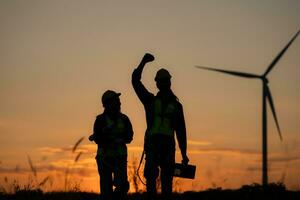 silhouette di ingegnere nel caricare di vento energia contro un' sfondo di vento turbine. foto