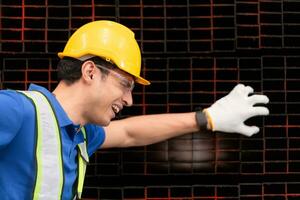 ritratto di un' maschio lavoratore indossare un' sicurezza veste e casco seduta su un' acciai pallet dovuto per indietro dolore a partire dal Lavorando nel un' fabbrica sollevamento pesante le cose. foto