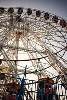 avvicinamento di multicolore gigante ruota durante Dussehra mela nel delhi, India. parte inferiore Visualizza di gigante ruota oscillazione. ruota panoramica con colorato cabine durante giorno volta. foto