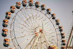 avvicinamento di multicolore gigante ruota durante Dussehra mela nel delhi, India. parte inferiore Visualizza di gigante ruota oscillazione. ruota panoramica con colorato cabine durante giorno volta. foto