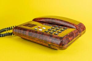 Vintage ▾ telefono nel imitazione radica legna al di sopra di un' giallo sfondo foto