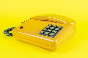 giallo plastica Vintage ▾ telefono con rosso pulsante su un' giallo sfondo foto