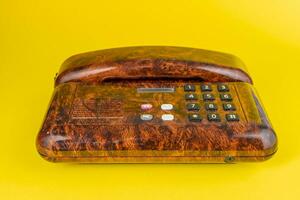 Vintage ▾ telefono nel imitazione radica legna al di sopra di un' giallo sfondo foto