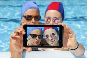 moderno mamma e giovane figlia prende un' autoscatto nel nuoto piscina. concetto di bellissimo persone avendo divertimento nel estate foto