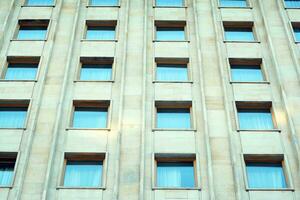 astratto avvicinamento di il rivestito di vetro facciata di un' moderno edificio coperto nel riflessivo piatto bicchiere. architettura astratto sfondo. bicchiere parete e facciata dettaglio. foto