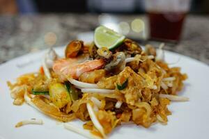 colpetto tailandese, riso tagliatelle fritte con tofu, verdura, uovo e frutti di mare. foto