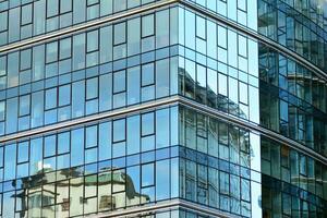 bicchiere edificio con trasparente facciata di il edificio e blu cielo. strutturale bicchiere parete riflettendo blu cielo. astratto moderno architettura frammento. contemporaneo architettonico sfondo. foto